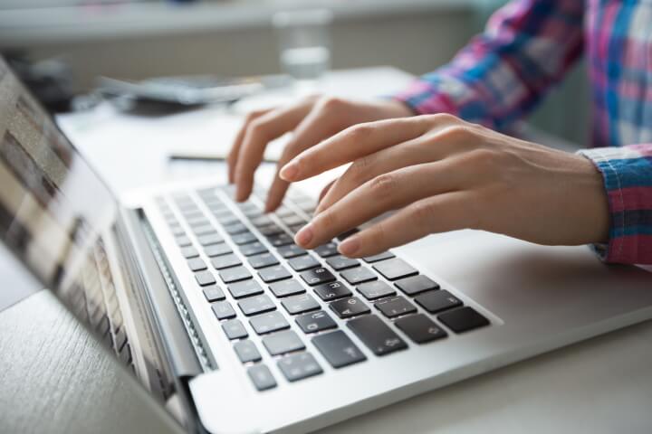 A pair of hands typing on a laptop